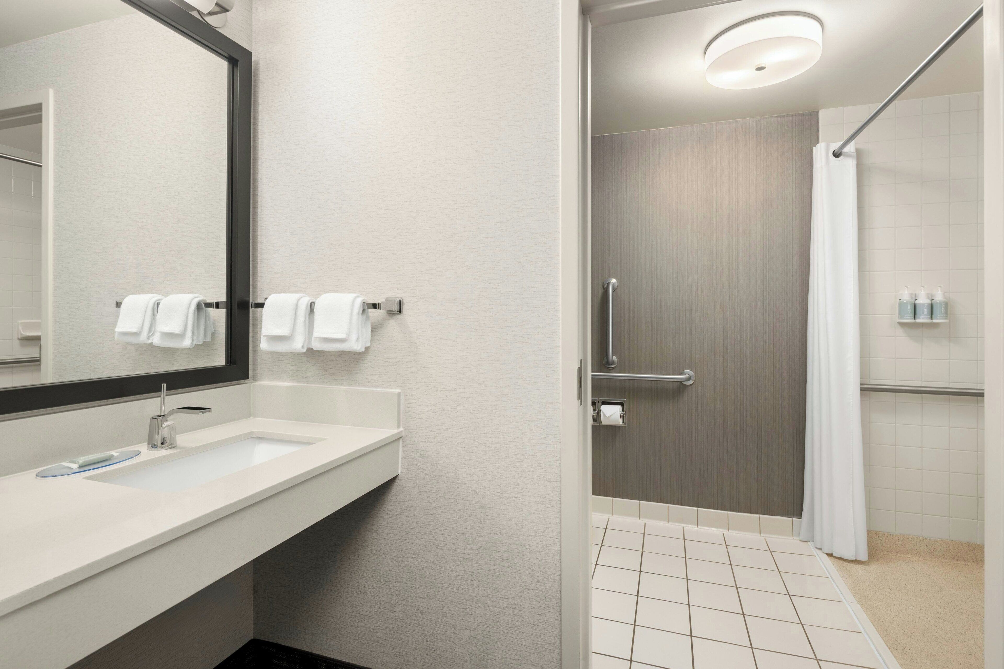 A modern bathroom with a large mirror, a sink, and a shower area.