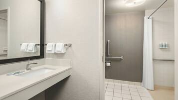 A modern bathroom with a large mirror, a sink, and a shower area.