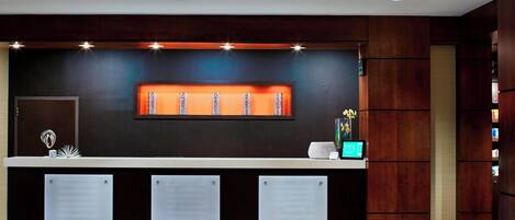 A reception desk with a dark wood finish, a glass panel, and a digital display.