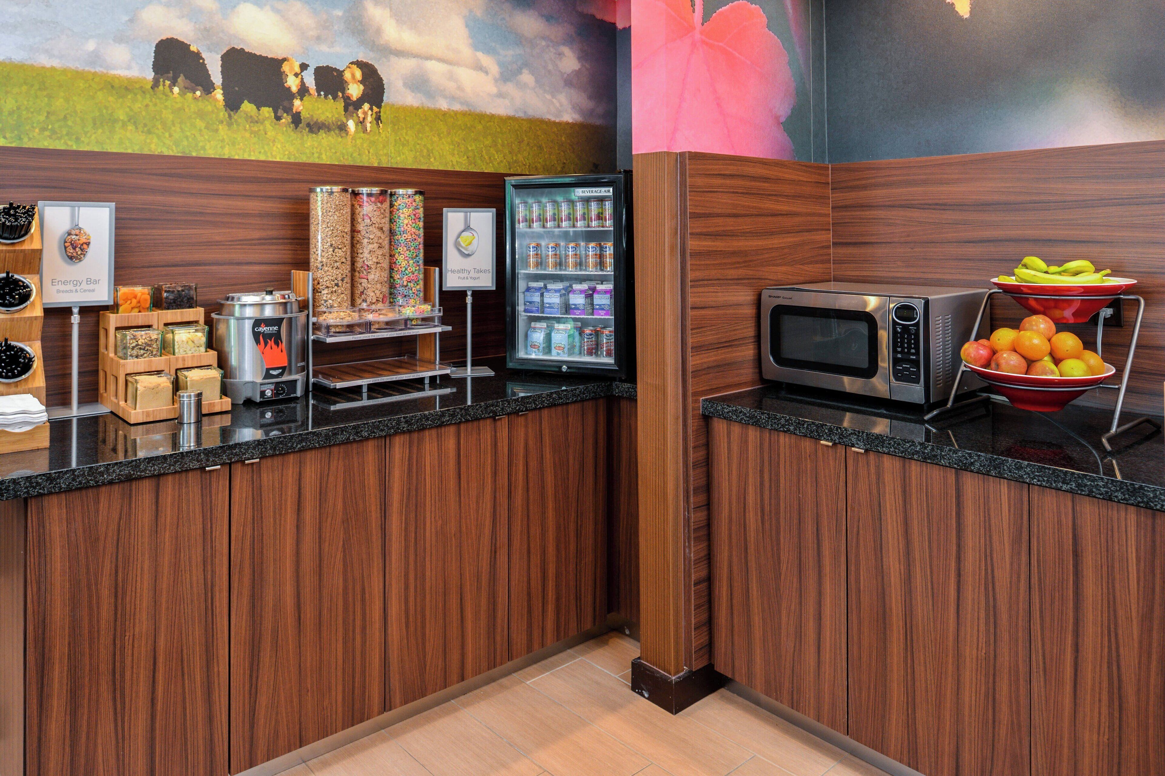 A kitchen area with a microwave, energy bar station, and a refrigerator.