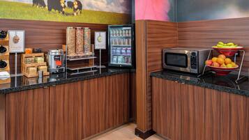 A kitchen area with a microwave, energy bar station, and a refrigerator.