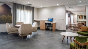Un hall d’hôtel moderne comprenant un espace salon, un bureau avec un ordinateur et un coin repas.
