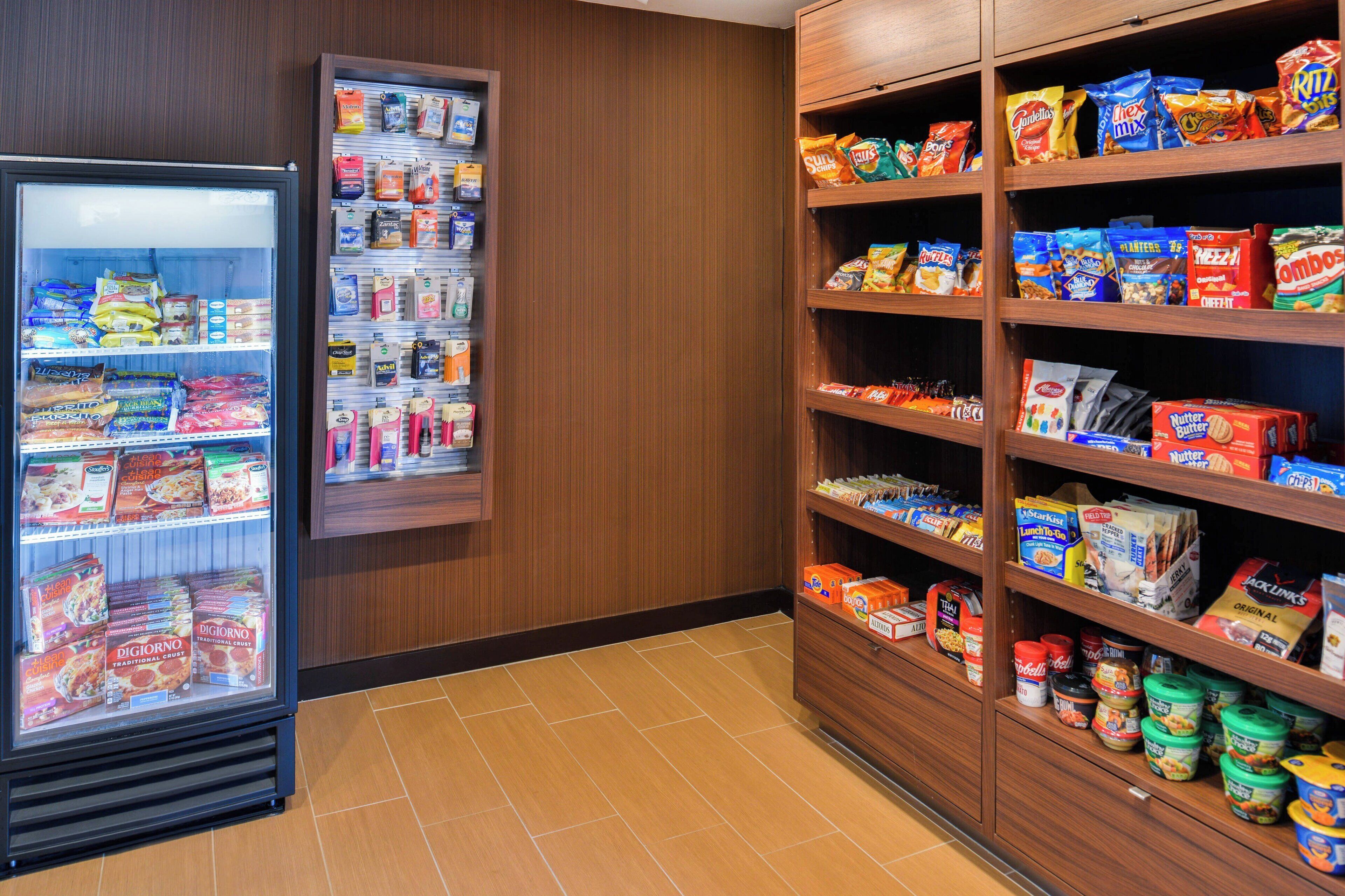 Zona de aperitivos y bebidas autoservicio con productos refrigerados y almacenados en estanterías.