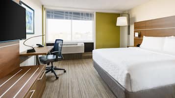 Una camera d'albergo con un letto, una scrivania, una sedia e una grande finestra.
