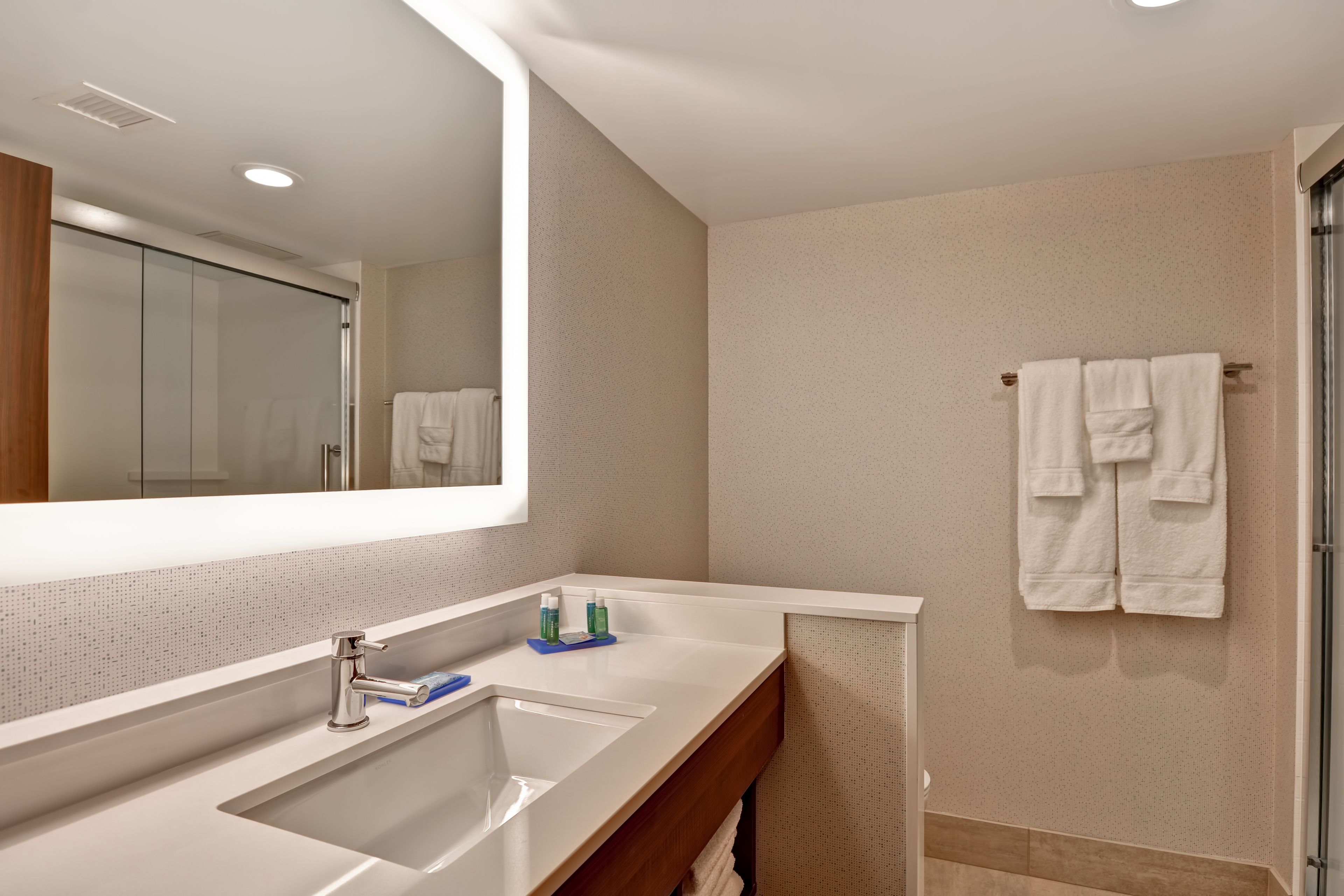 A modern bathroom with a large mirror, a sink, and a towel rack.
