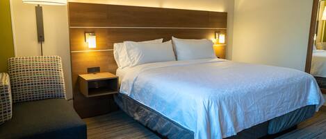 A hotel room with a bed, a nightstand, a chair, and a lamp.