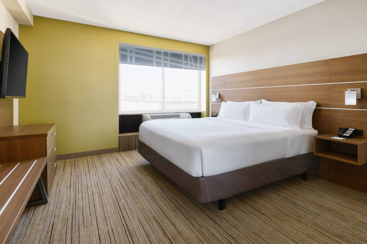 Een hotelkamer met een bed, nachtkastje en een aan de muur bevestigde televisie.