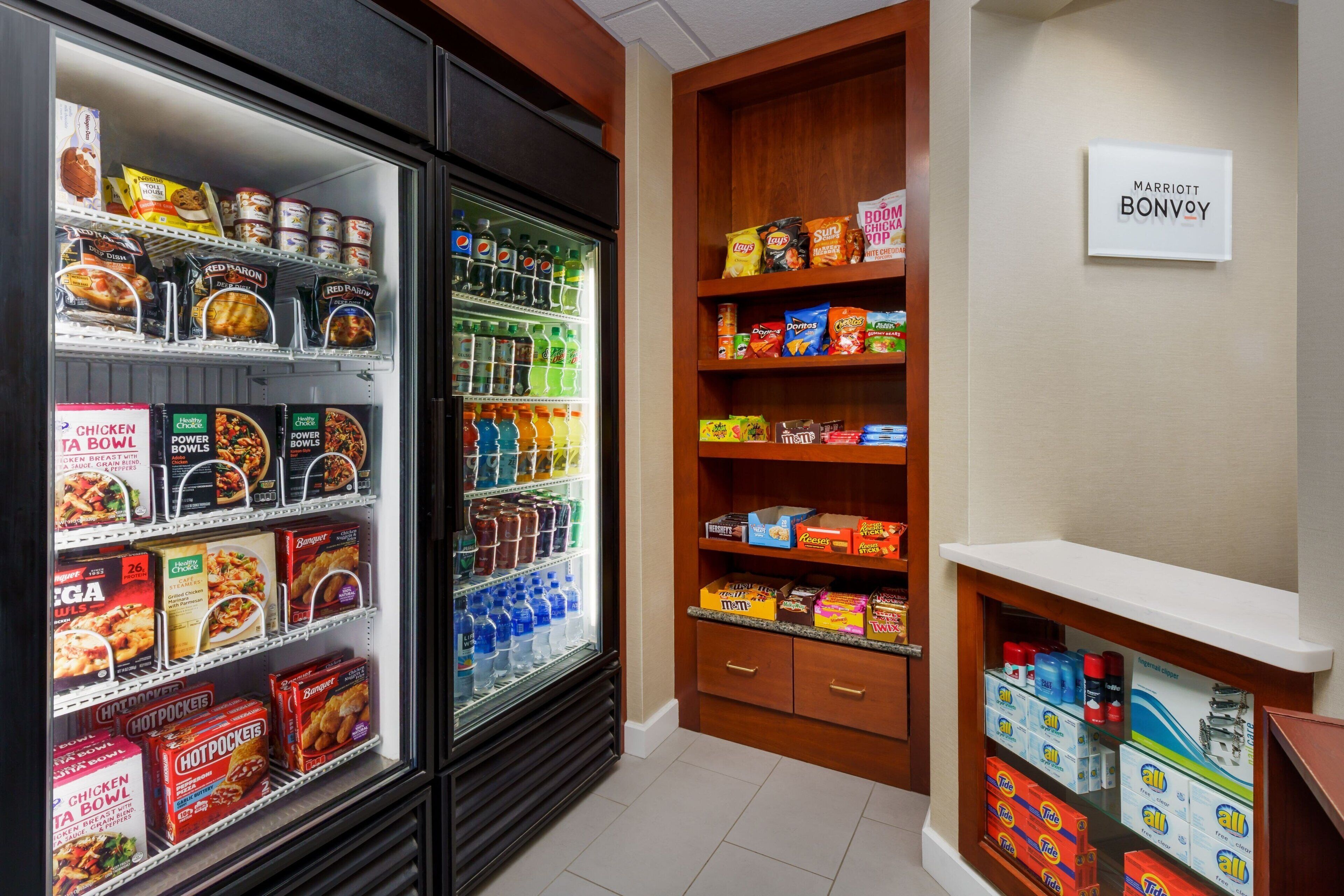 Habitación de hotel con un minibar repleto de aperitivos, bebidas y aderezos.