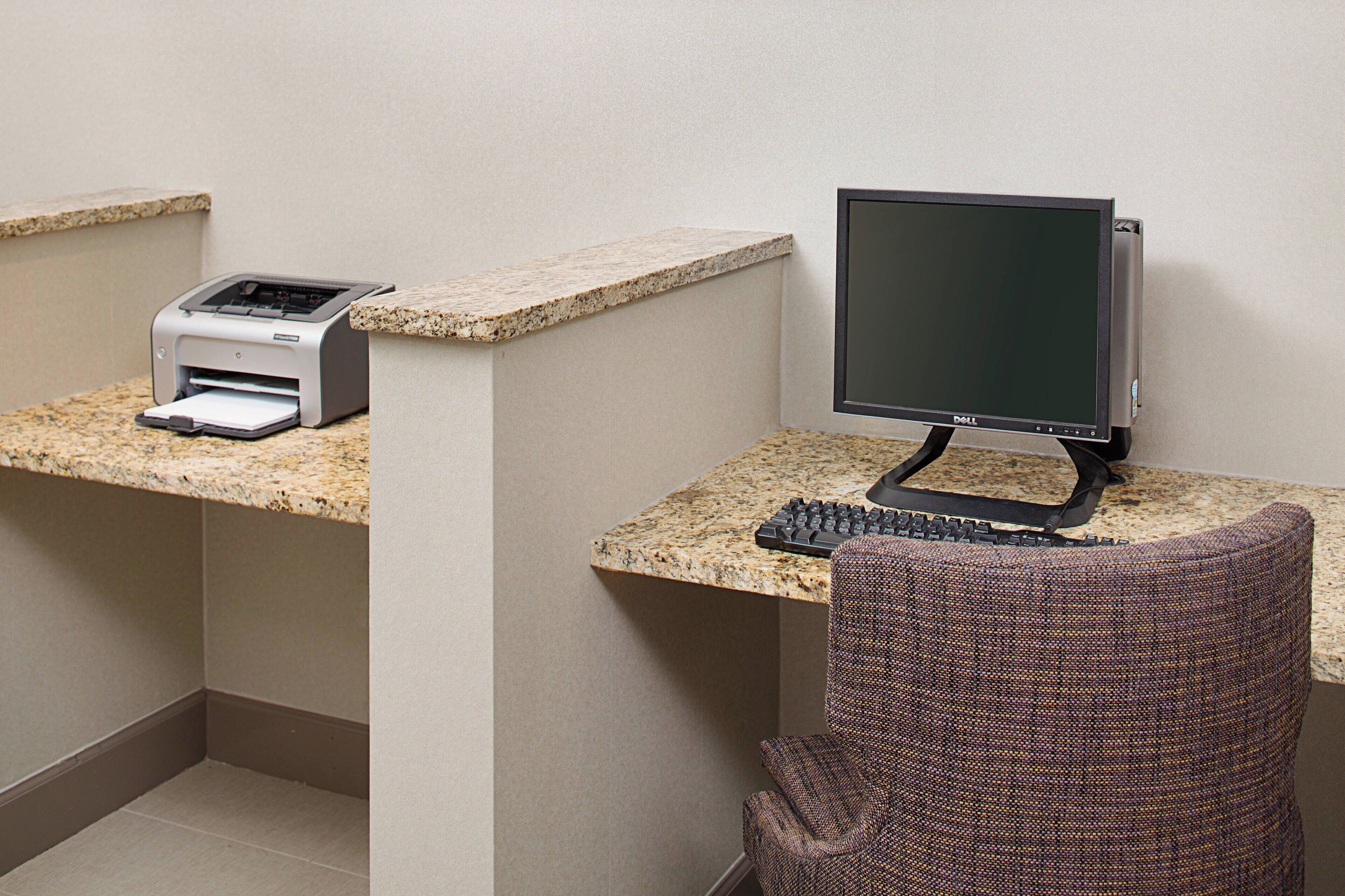 Ein Arbeitsplatz mit einem Desktop-Computer, Tastatur und einem Drucker auf einer Granit-Arbeitsplatte.