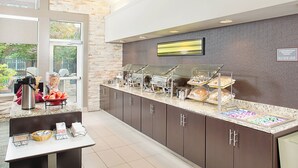 A buffet area with a variety of food options, a coffee station, and a large window providing a view of the outdoors.