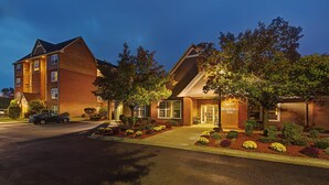 A hotel with a brick facade, multiple windows, and a well-maintained garden with various plants and shrubs.