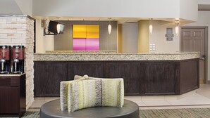 A modern hotel lobby with a bar area, seating, and a large mirror.