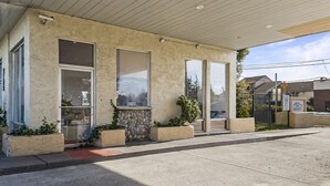 Un bâtiment doté d’une façade en pierre, de grandes fenêtres et d’un espace d’entrée abrité agrémenté de plantes en pot.