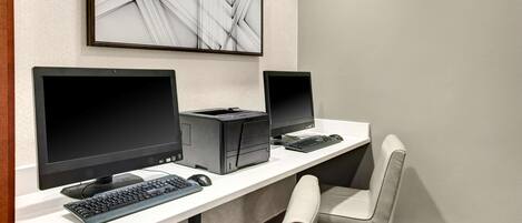A workspace with two monitors, a keyboard, a printer, and a chair.