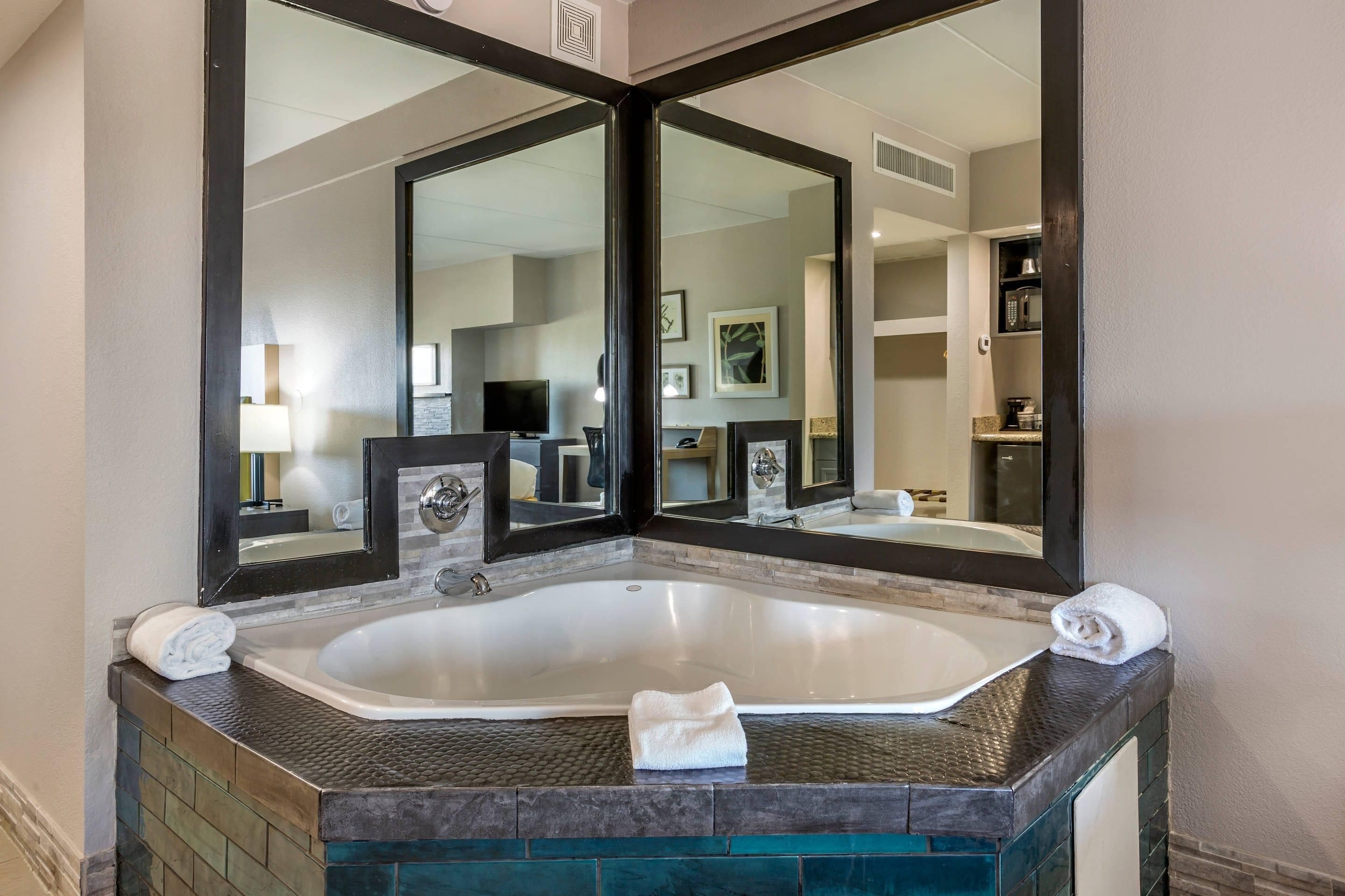 Une salle de bain avec une grande baignoire, un miroir et un lavabo.