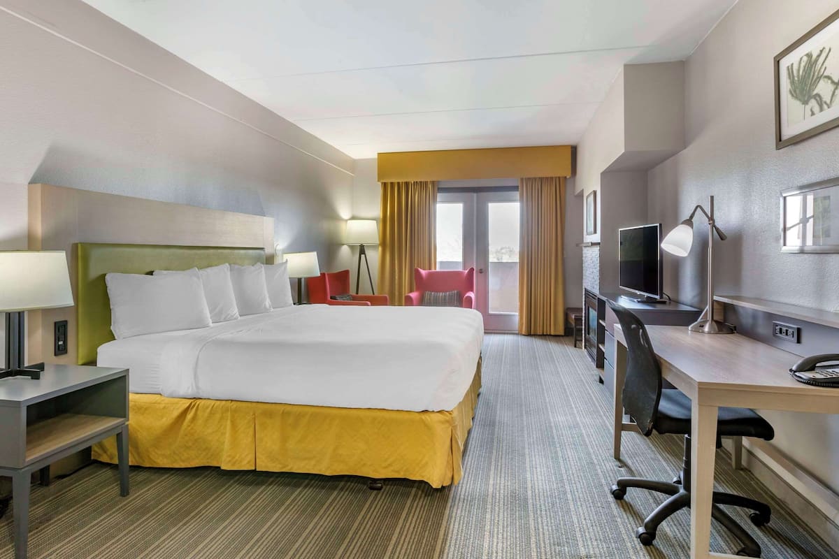 A hotel room with a large bed, a desk with a computer, a TV, and a chair.