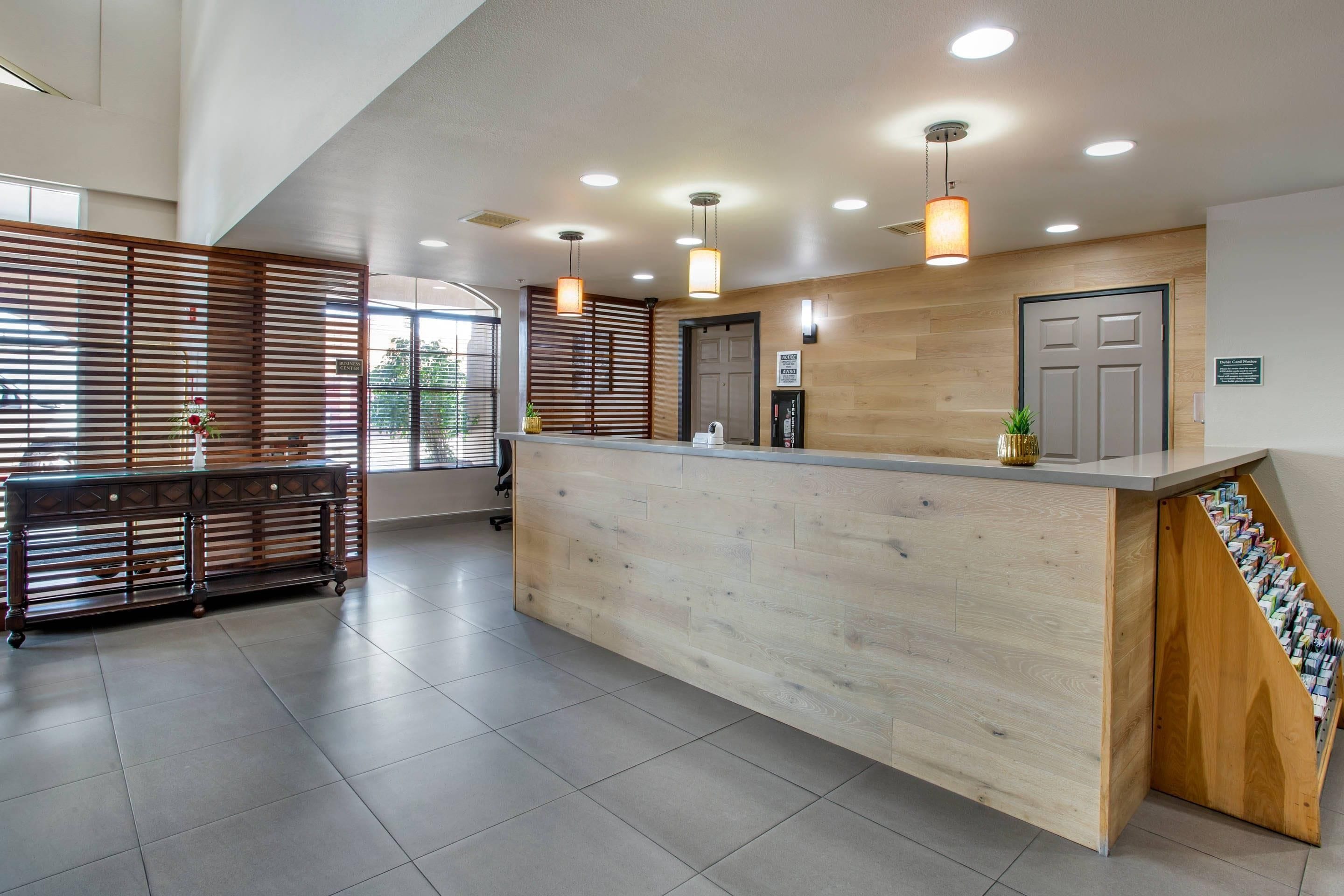 Un mostrador de recepción con detalles de madera, un área de espera con un banco y una puerta con un letrero.