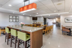 A modern dining area with a central island, multiple seating options, and a flat-screen TV mounted on the wall.