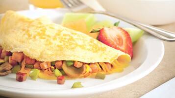 A breakfast plate with an omelette, vegetables, and a glass of orange juice.