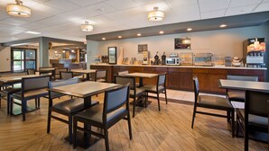 A restaurant interior with wooden flooring, tables, and chairs. There is a counter with a menu board and a fruit juice dispenser. - Best Western Plus Coldwater Hotel (Coldwater)