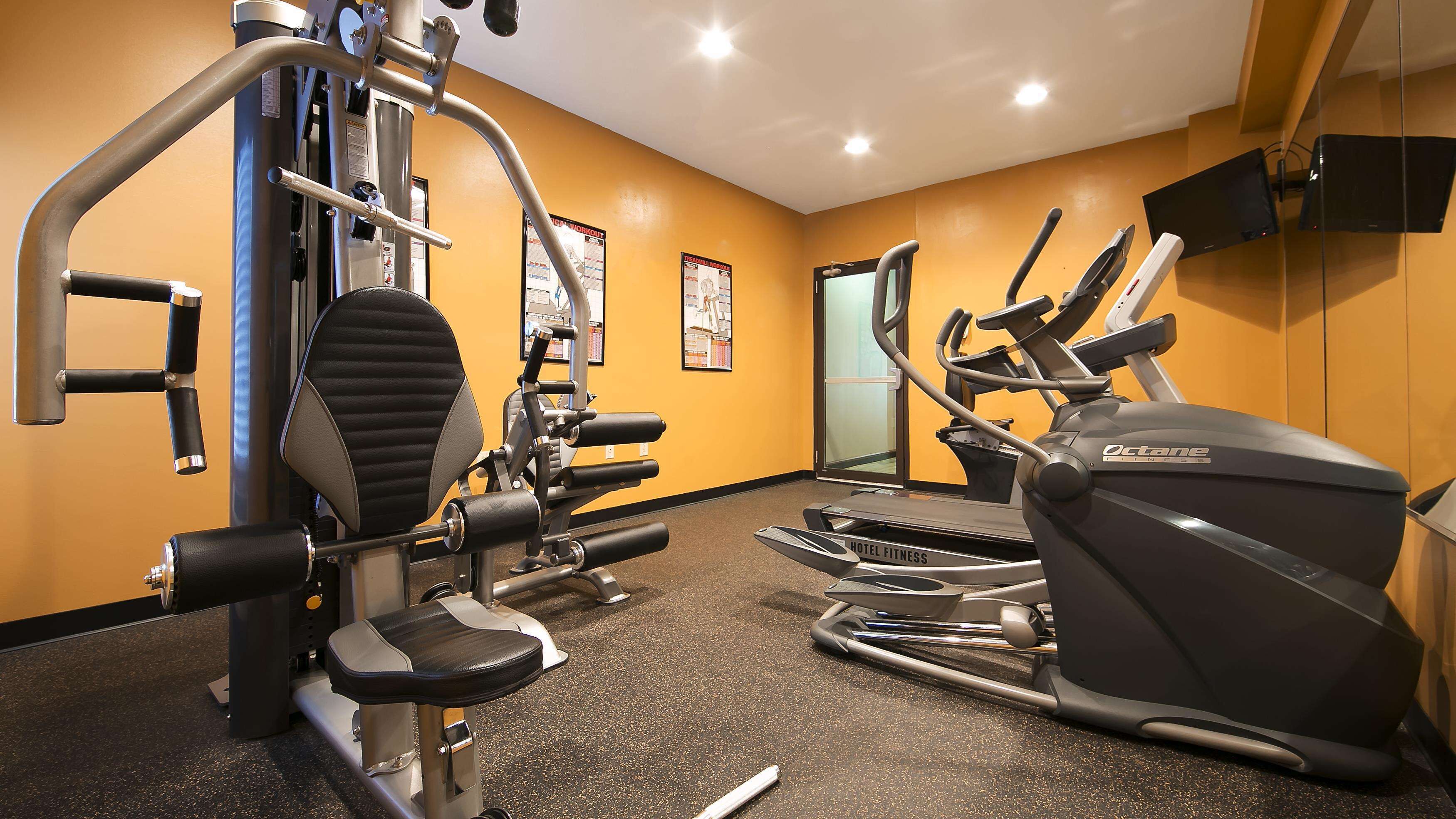 A hotel fitness center with various exercise equipment, including a leg press, a bench press, and a treadmill.