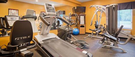 Gimnasio de hotel con cintas de correr, máquinas de pesas y una máquina de remo.