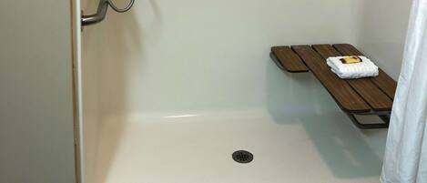 Un área de ducha con un banco y una toalla.