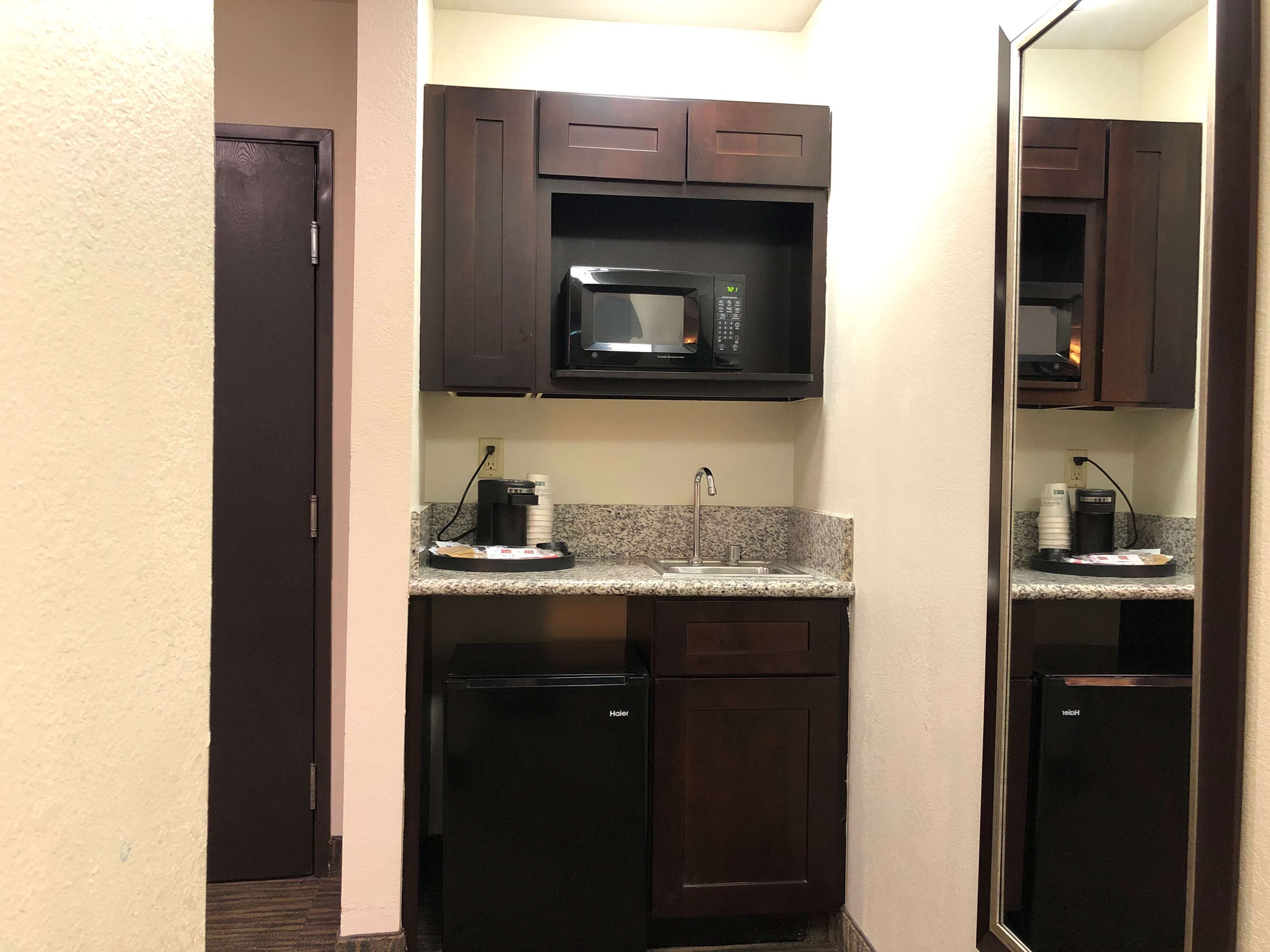 A compact kitchenette with a microwave, coffee maker, and a small refrigerator.