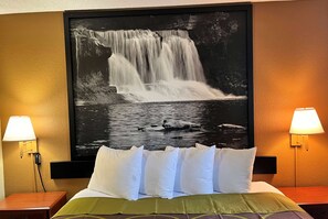 A hotel room with a large waterfall painting on the wall, a bed with white and green bedding, and two bedside lamps. - Super 8 by Wyndham Indianapolis/NE/Castleton Area (Indianapolis)