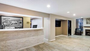 A reception area with a stone counter, a framed welcome sign, and a flat-screen TV.