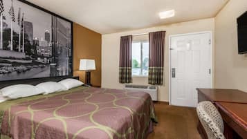 A hotel room with a large bed, a desk, a chair, a window with curtains, and a wall-mounted TV.