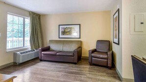 A living room with a brown leather sofa, a brown leather armchair, a framed picture on the wall, and a window with curtains. - Extended Stay America Suites Nashville Franklin Cool Springs (Franklin)