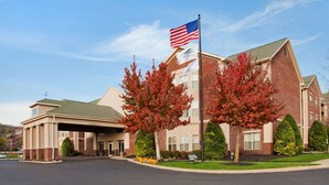 A hotel with a brick facade, a covered entrance, and a flagpole with an American flag. - Homewood Suites by Hilton Nashville-Brentwood (Brentwood)