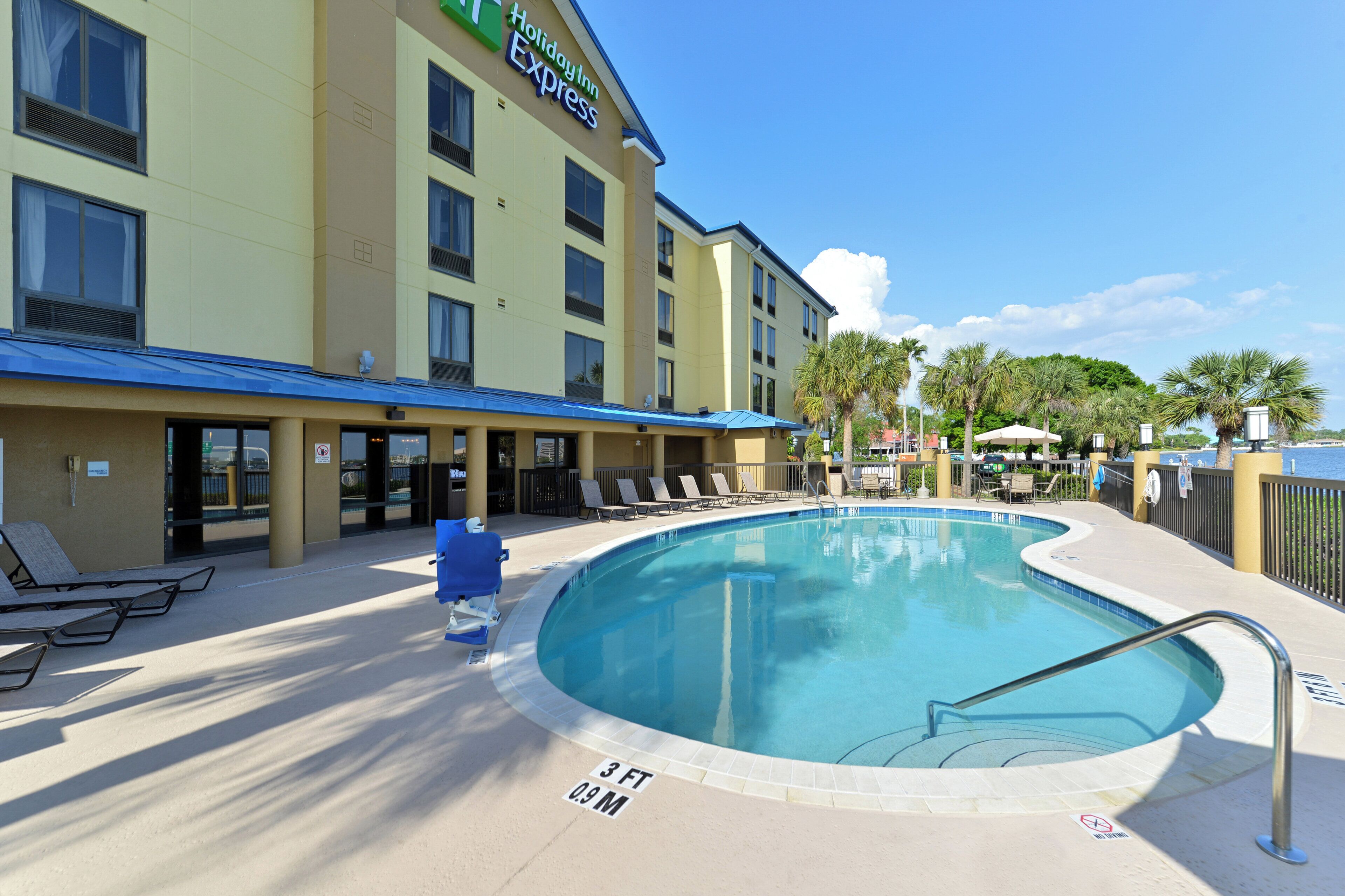 A Holiday Inn Express with a pool area, including lounge chairs and a clear blue pool.