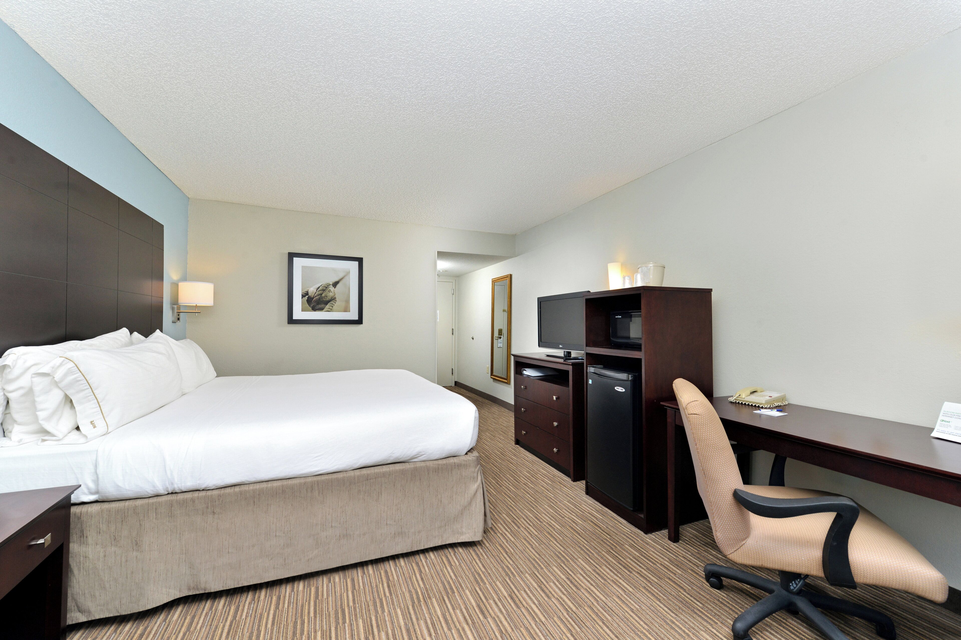 Une chambre d’hôtel équipée d’un lit, d’un bureau, d’une chaise et d’un téléviseur.