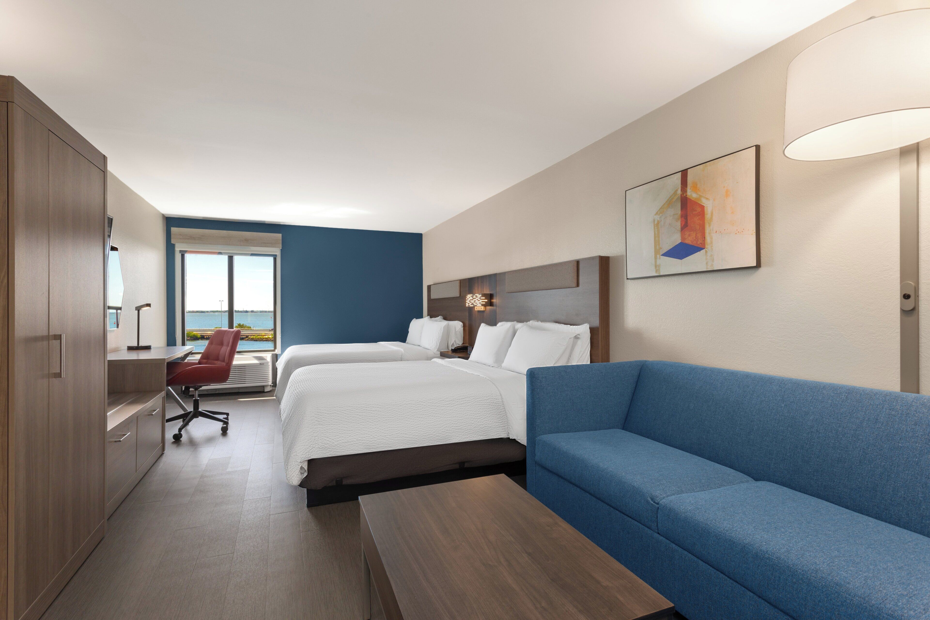 Una habitación de hotel con una cama, un sofá azul, un escritorio y una silla.