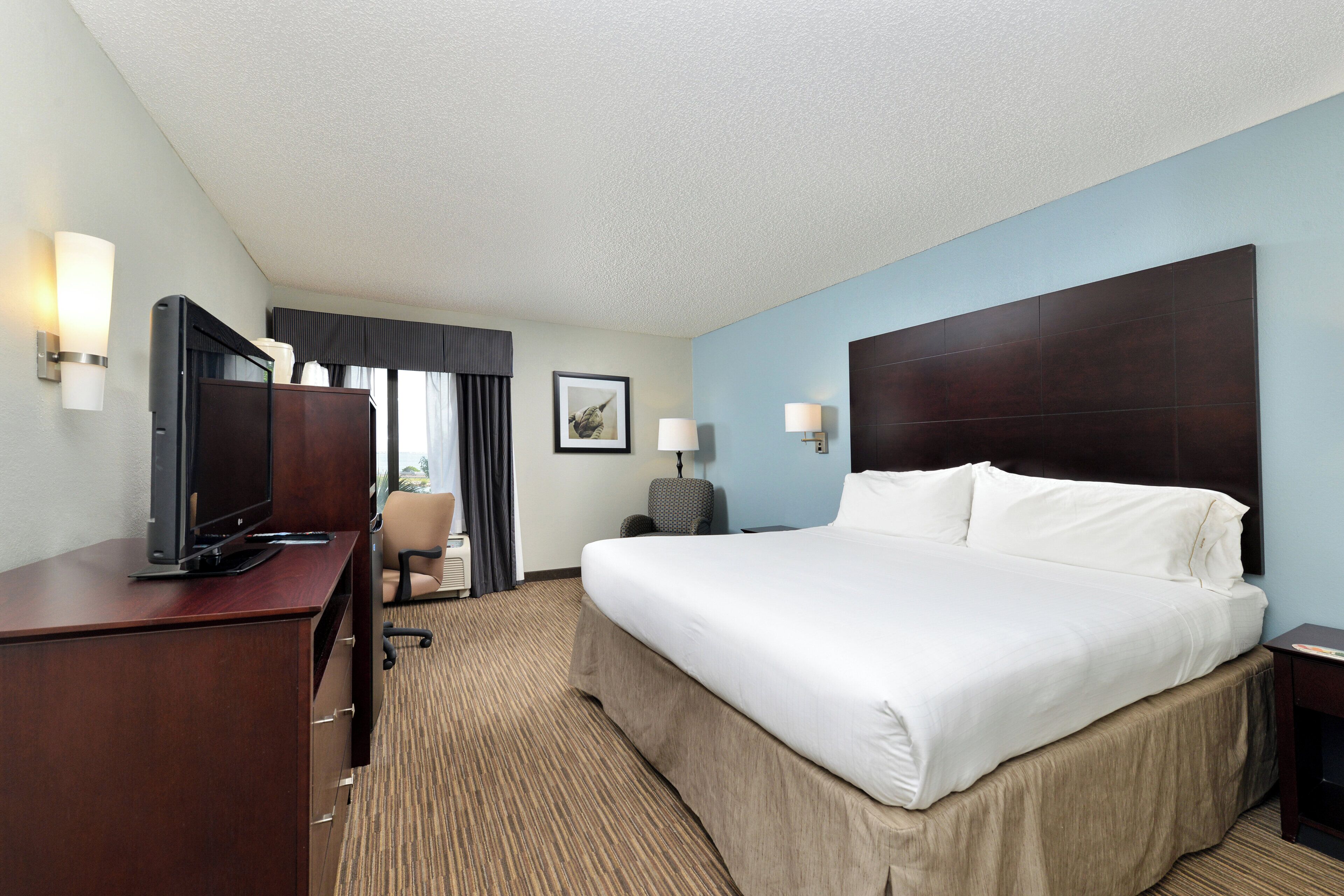Une chambre d’hôtel équipée d’un lit, d’un bureau, d’une chaise et d’un téléviseur.