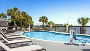 A swimming pool with lounge chairs and a sun umbrella. - Holiday Inn Express Hotel & Suites Tampa-Rocky Point Island by IHG (Tampa)