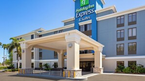 A Holiday Inn Express & Suites building with a covered entrance, palm trees, and a clear blue sky. - Holiday Inn Express Hotel & Suites Tampa-Rocky Point Island by IHG (Tampa)