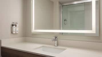 A bathroom with a white sink, a mirror, and two Dove body lotion dispensers.