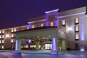 Um hotel com entrada coberta, vários andares e janelas iluminadas.