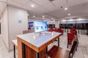Centre de negocis modern amb un ordinador, zona de seients i un senyal que indica operació les 24 hores.