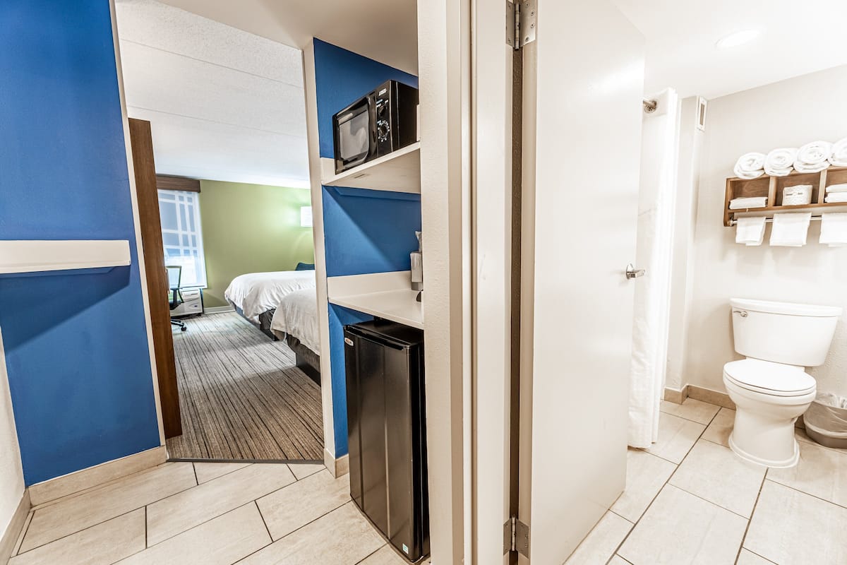 Camera d'albergo con un letto, forno a microonde, mini-frigorifero e bagno con il water e portasciamani.
