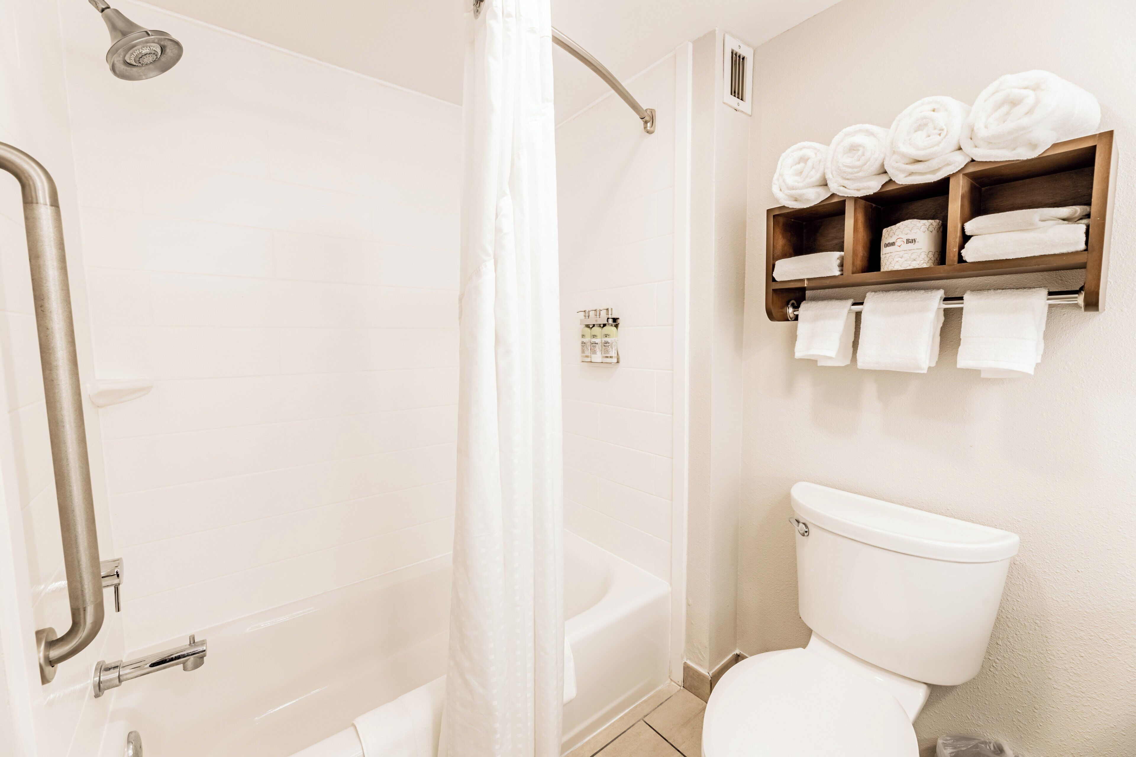 A bathroom with a shower, toilet, and a shelf with towels.