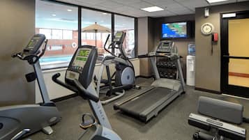 Ein Fitnessraum mit Laufbändern, einem Crosstrainer und einem stationären Fahrrad.