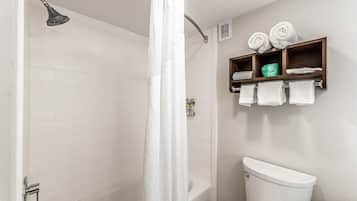 A bathroom with a shower, a toilet, and a shelf with towels.