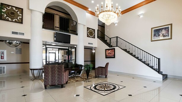 A spacious lobby with a chandelier, a staircase, and a reception desk.