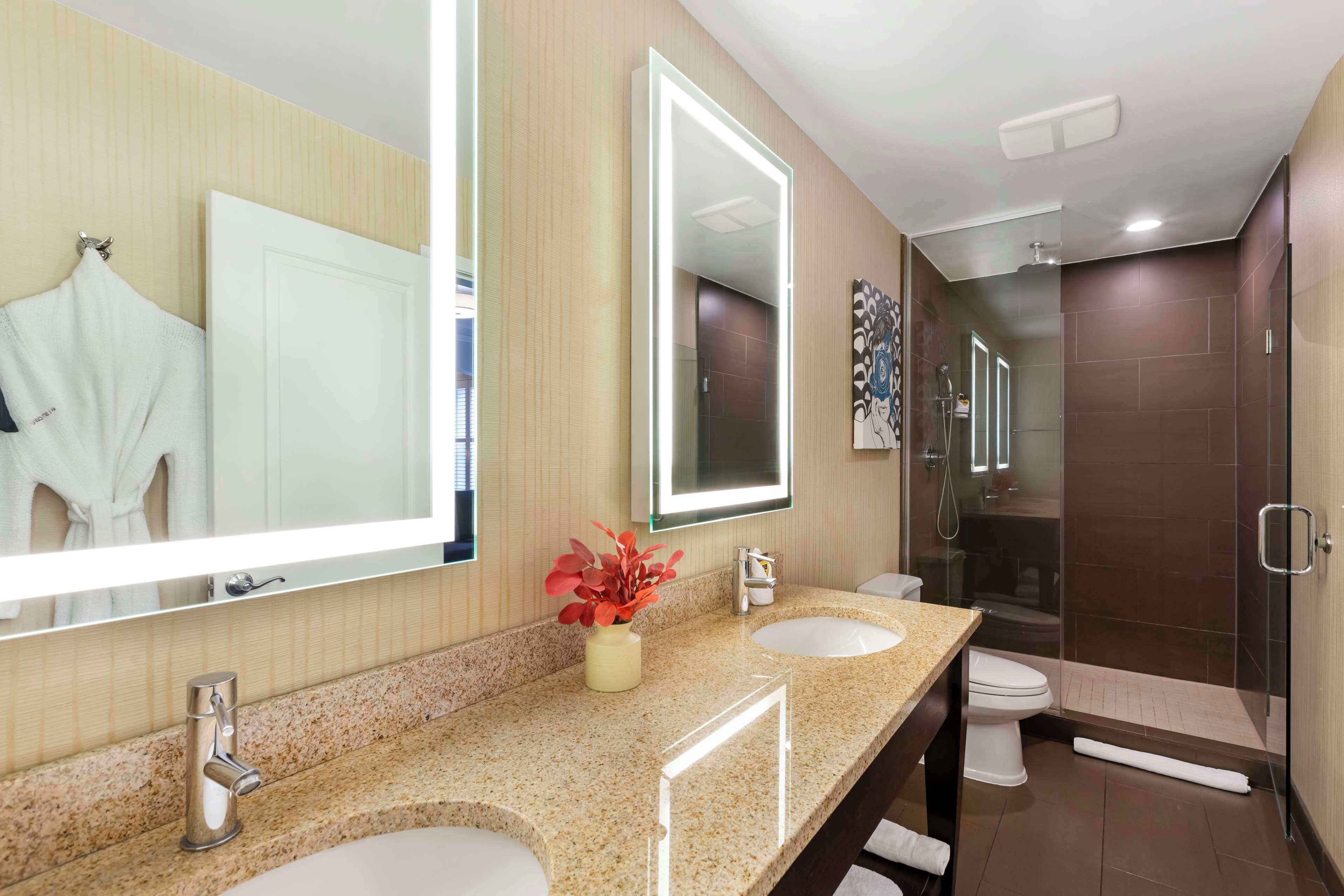 A modern bathroom with two sinks, a large mirror, and a shower area.