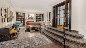 A spacious living room with a fireplace, a staircase, and a bookshelf.