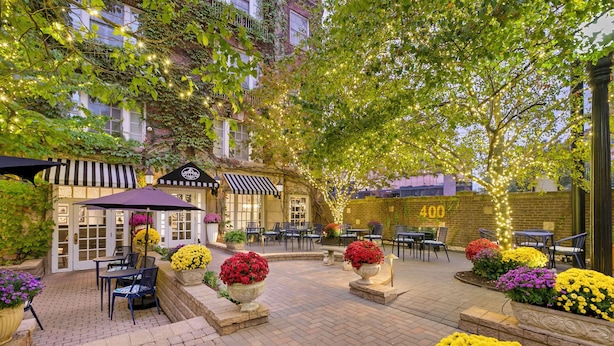 An outdoor patio area with brick flooring, outdoor seating, and potted plants.
